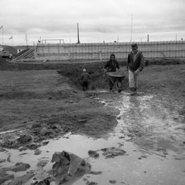 Photograph of men pushing wheelbarrows at a construction site in Fort Chimo, Quebec