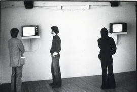 Photograph of three people watching televisions in the gallery at the Centre for Art Tapes