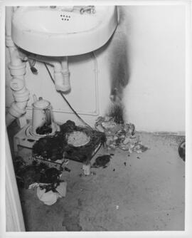 Photograph of a fire-scorched hotplate underneath a sink