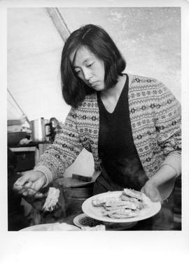 Photograph of an unidentified woman serving food