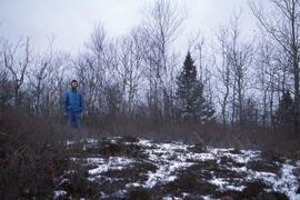 Photograph of an unidentified researcher standing in a Canada Land Inventory (CLI) "unproductive ...