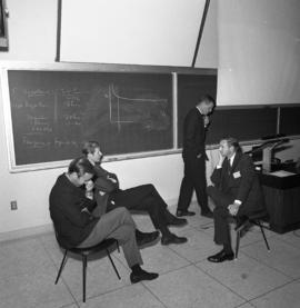 Photograph of four unidentified people in a classroom