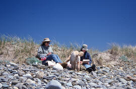 Photograph of two unidentified people and a dog picnicking on the Gaff Point trail, near Kingsbur...