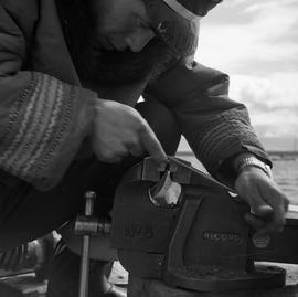 Photograph of a man working with a vice in Fort Chimo, Quebec