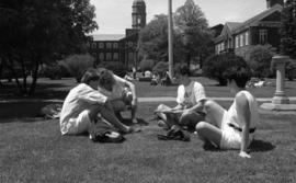 Photograph of students sitting on the lawn in front of the Henry Hicks Building