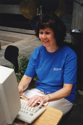 Item is a photograph of a librarian Alison MacNair working at the Killam Web Café
