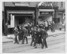 Photograph of servicemen and women walking past looted shops on Barrington Street in the aftermat...