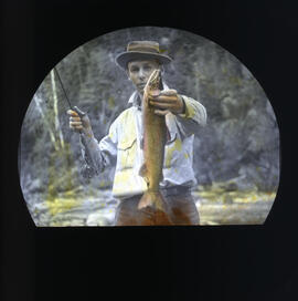 Photograph of an unidentified man holding a rainbow trout and fishing rod