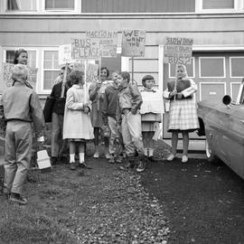 Photograph of children holding signs about a bus