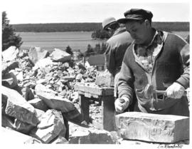Photograph of a stonecutter shaping rock for the new wing of Men's Residence Howe Hall