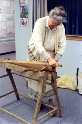 Photograph of Barbara Hinds breaking flax at a demonstration