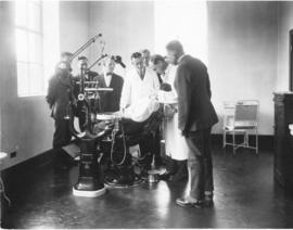 Photograph of men observing a dental examination in the public health clinic
