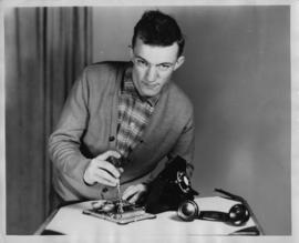Photograph of David Guy working on a telephone
