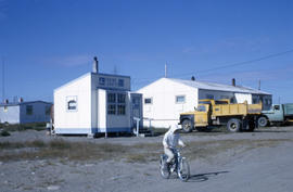 Photograph of a boy riding a bicycle next to a shop called "Eskimo Crafts"
