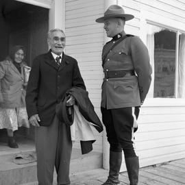 Photograph of an elderly man in a suit standing with a Mountie in Dawson City, Yukon