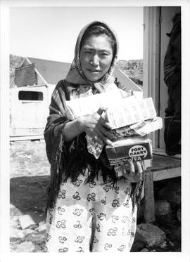 Photograph of an unidentified woman holding a pile of tea and other supplies