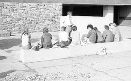Photograph of people sitting on a bench outside the Killam Memorial Library
