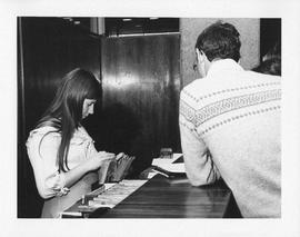 Photograph of an unidentified person using the circulation system in the Killam Library