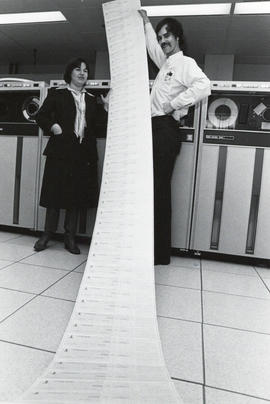 Photograph of Paula McNeill and John Pallas with long paper print-out