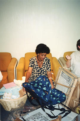 Item is a photograph of Asmeret Gheabreab opening gifts at a group baby shower held in the staff ...