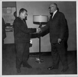 Photograph of installer Ray Jollimore being congratulated by district plant superintendent upon h...