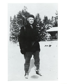 Photograph of Thomas Head Raddall holding a rifle in the winter at Eagle Lake