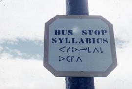 Photograph of a bus stop sign in English and Inuktitut syllabics
