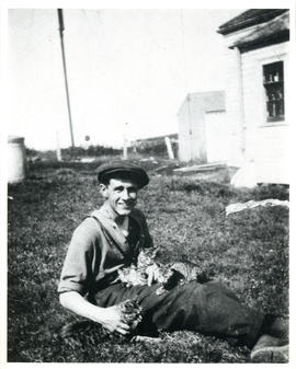 Photograph of Thomas Head Raddall holding several cats outside Camperdown wireless station