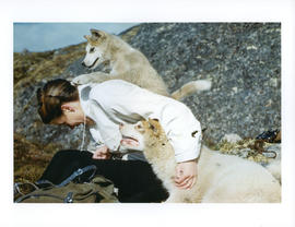 Photograph of Barbara Hinds playing with two white dogs