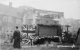 Postcard replica of photograph of a parade float bearing a model of the original Dalhousie Colleg...