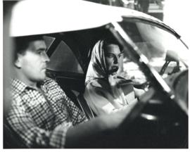 Photograph of "Neil" (James Doohan) sitting in the passenger seat of a car driven by "Paula" (Lad...