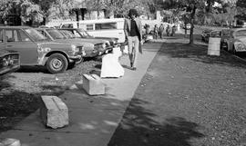 Photograph of a man walking on a sidewalk with large stone blocks on it