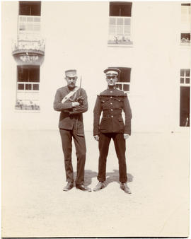Photograph of two officers in uniform standing outside of the officers' quarters at Hythe, England