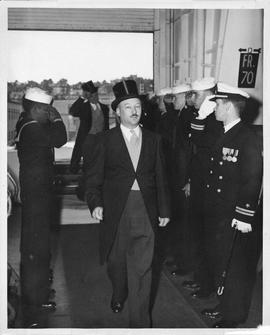 Photograph of Henry Hicks walking past saluting sailors