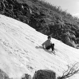 Photograph of a woman sliding down a snowy hill in the Yukon