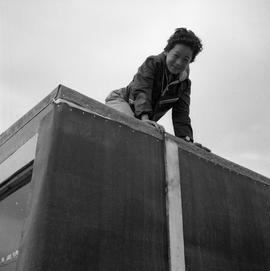 Photograph of a boy on the roof of Alicie Berthé's house in Fort Chimo, Quebec