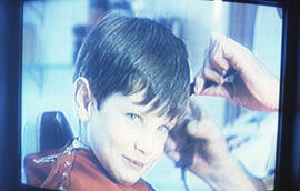 Photograph of a child gazing into the camera on a television screen