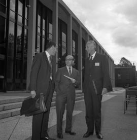 Photograph of three unidentified people standing in front of the Tupper Building