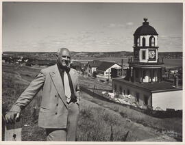 Photograph of Thomas Head Raddall standing on Citadel Hill with the Town Clock and Halifax Harbou...