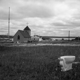 Photograph of a church and an abandoned toilet in Fort Chimo, Quebec