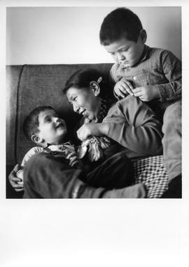 Photograph of a young woman and two children sitting on a sofa