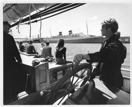 Photograph of sailboat deck with young man at the wheel