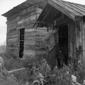 Photograph of an unidentified man looking into a shed in the Yukon