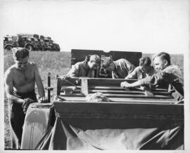 Photograph of five unidentified soldiers conducting maintenance on a 25-pound howitzer at Tracadi...