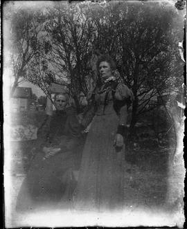 Photographic negative of a pair of women posing on a lawn