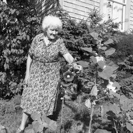 Photograph of Mrs. Farrant with hollyhocks