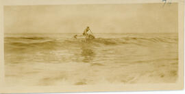 Photograph of a person aboard a barrel raft in a moderate swell off Sable Island