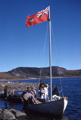 Photograph of several people in a boat that is flying a Canadian flag