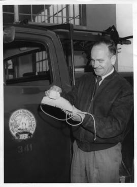Photograph of Sedley Thomas Mayo holding a telephone standing by truck
