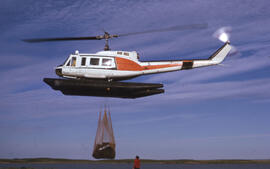 Photograph of Bill Freedman guiding a helicopter dropping off oil barrels at a control test site,...